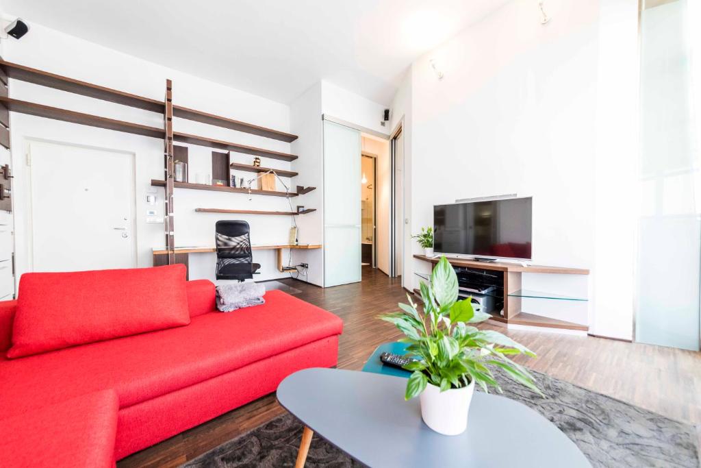 uma sala de estar com um sofá vermelho e uma televisão em Life Apartment & City Bike em Bolzano