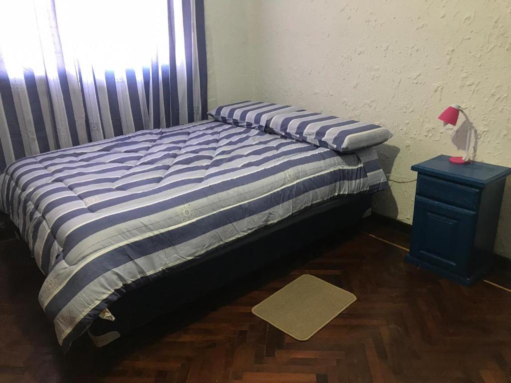 a bed with a blue and white striped comforter in a room at Hostal Bernardo Salta in Salta