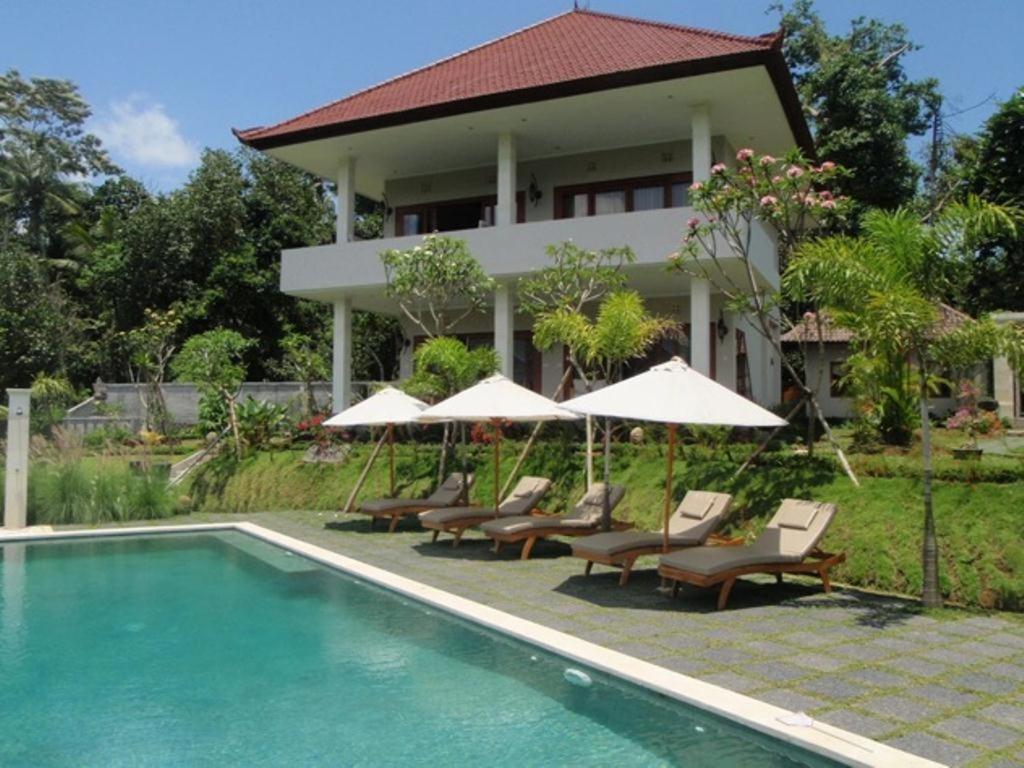 a resort with a swimming pool and chairs and umbrellas at Villa Shantiasa Bali in Sidemen