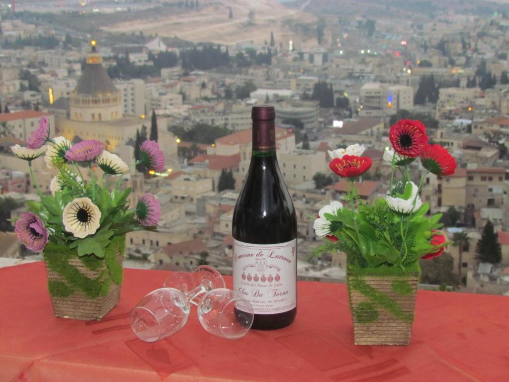 a bottle of wine and glasses on a table with flowers at Royal Guest House in Nazareth