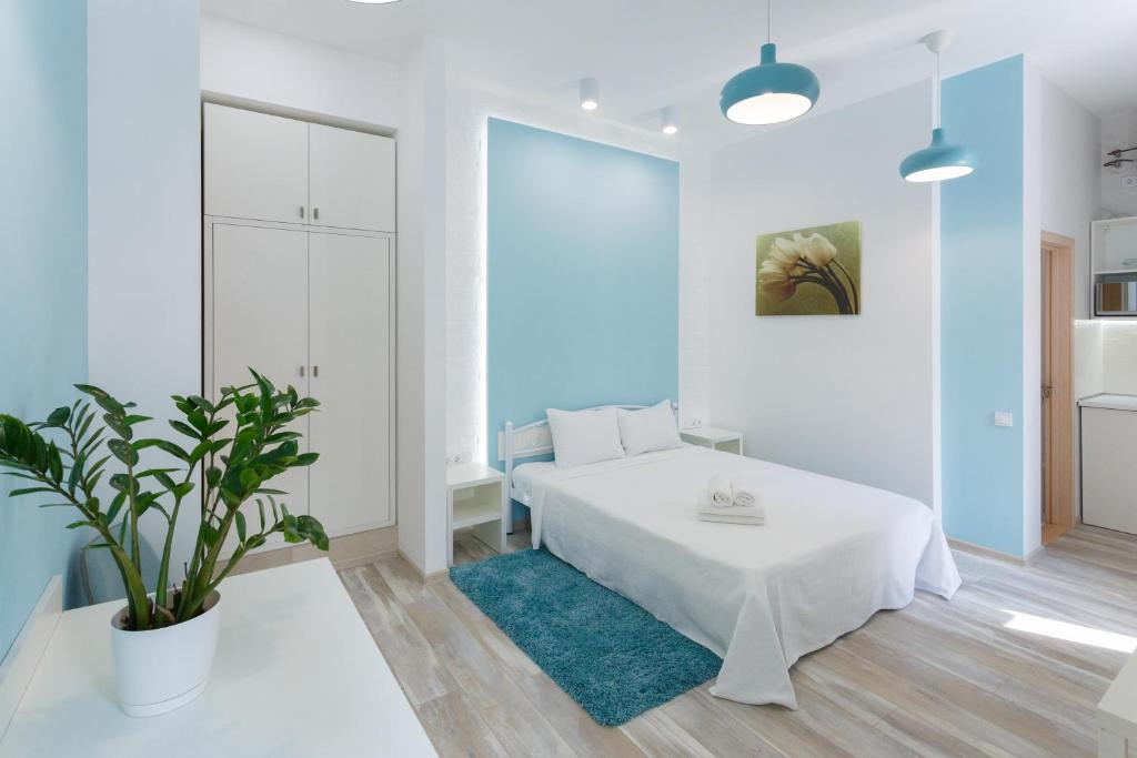 ein weißes Schlafzimmer mit einem Bett und einer Topfpflanze in der Unterkunft Basseynaya Apart Hotel in Kiew