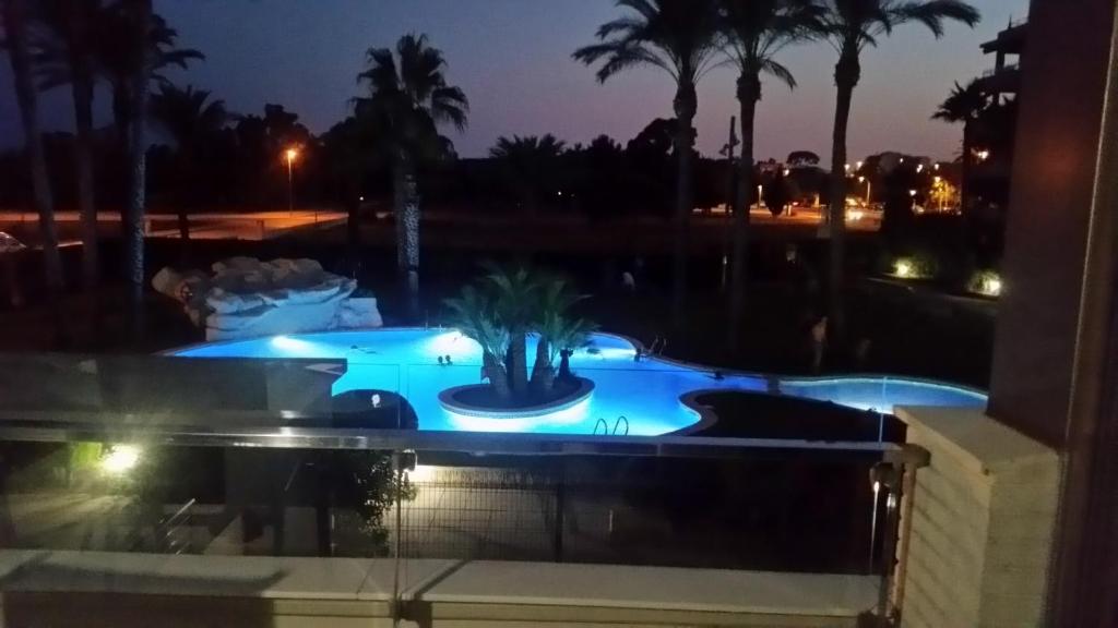 una piscina por la noche con una palmera en el medio en Torredembarra, en Torredembarra