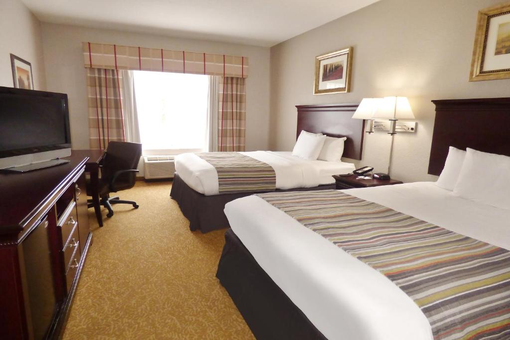 a hotel room with two beds and a flat screen tv at Country Inn & Suites by Radisson, Pensacola West, FL in Pensacola