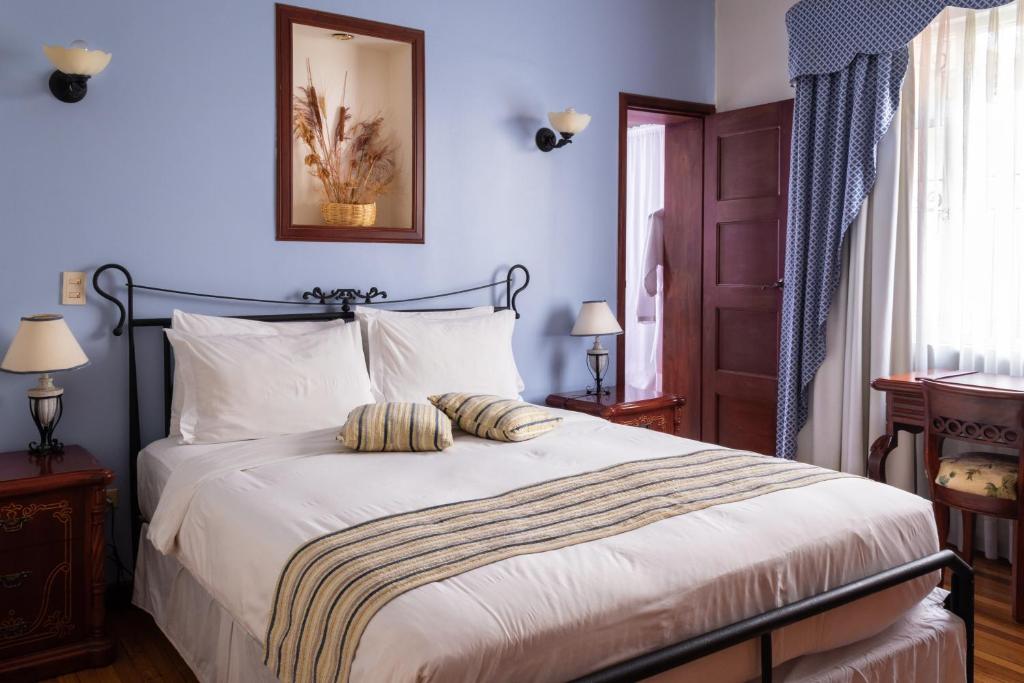 1 dormitorio con 1 cama grande con sábanas blancas en Casa Aliso Hotel Boutique, en Quito