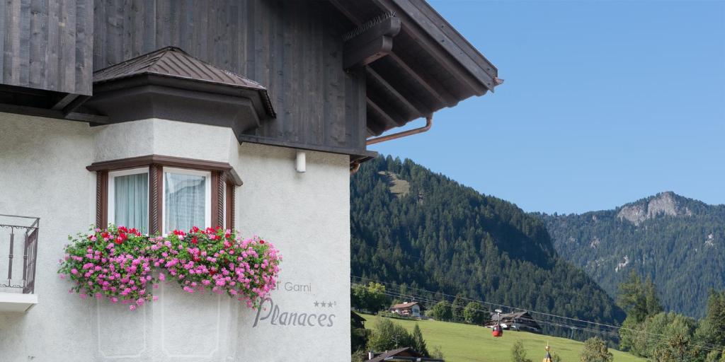 un edificio con una ventana con flores rosas. en Hotel Garni Planaces en Ortisei