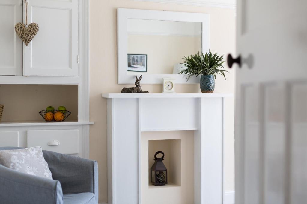 chimenea blanca en la sala de estar con silla en City Apartments - 4 Heworth Village - 3 bed house, en York