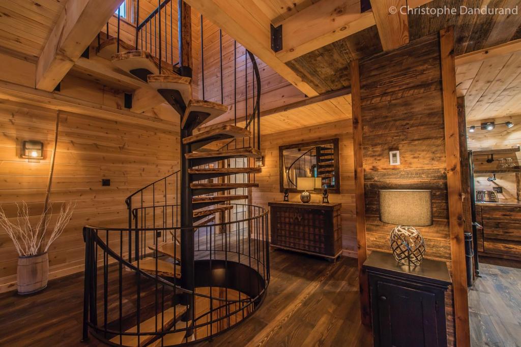 una escalera de caracol en una habitación con paredes de madera en Chalet TAO par Les Chalets Spa Canada, en La Malbaie