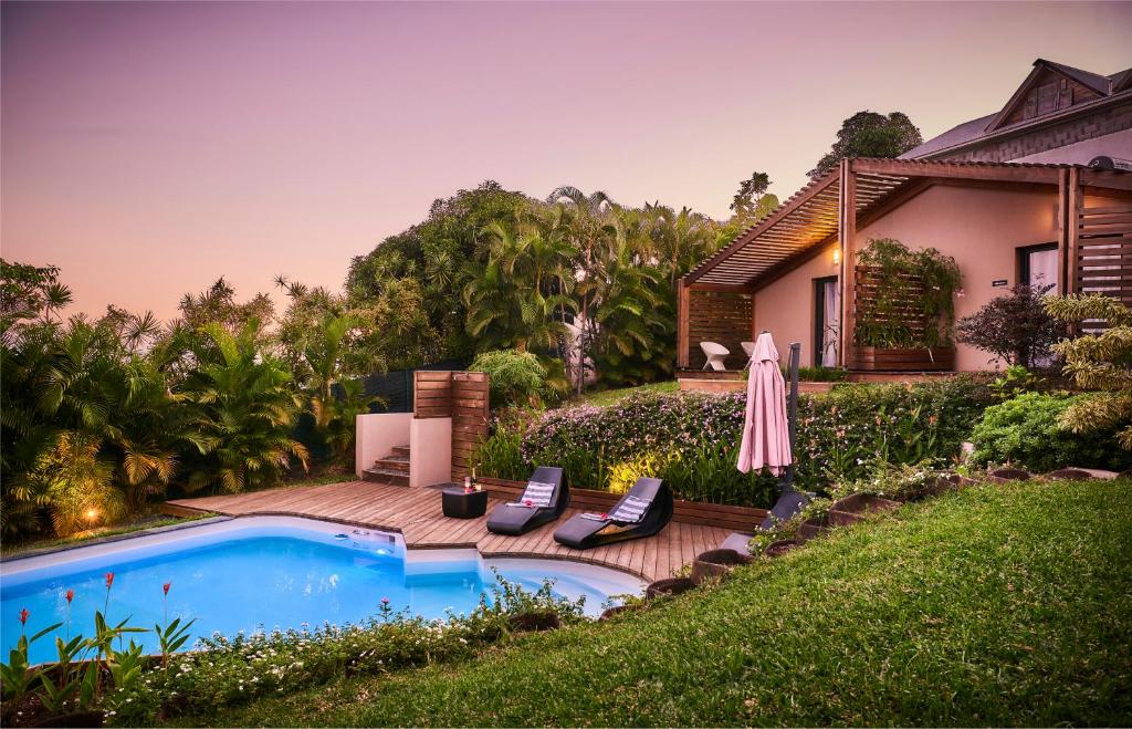 un patio trasero con piscina y una casa en Villa Romeo, en Étang-Salé