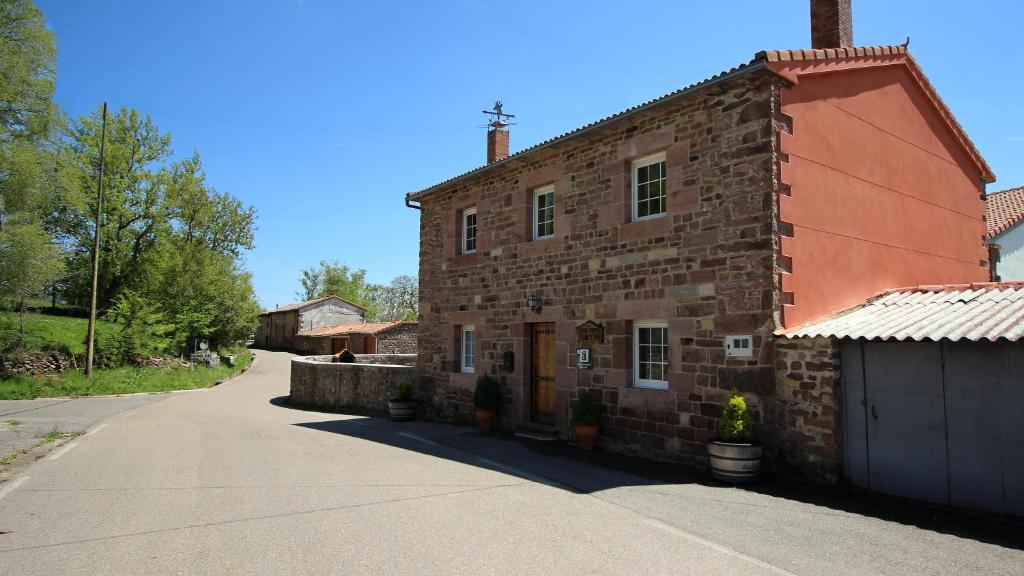 un antiguo edificio de ladrillo con una entrada delante de él en Casa Rural LA COVA, en Suano