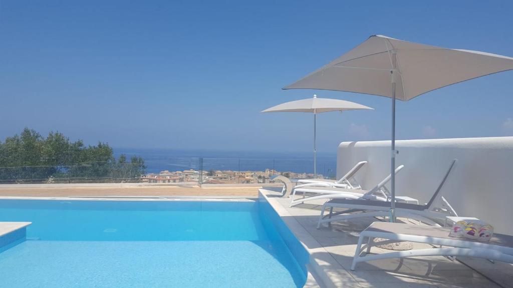 una piscina con due sedie e un ombrellone di Appartamenti Borgo Panoramico n.1 a Tropea