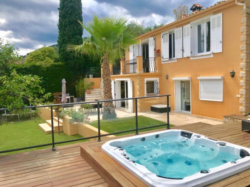 a hot tub on a deck in front of a house at Villa Grasse Avec Spa in Grasse