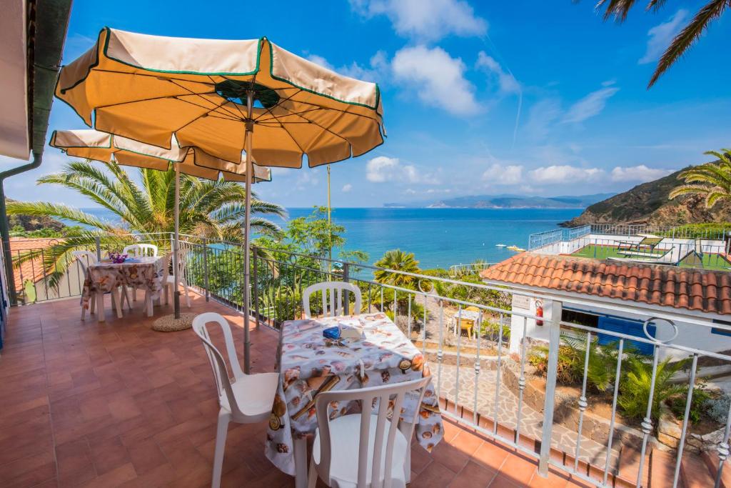 カポリーヴェリにあるResidential Hotel Villaggio Innamorataの海の景色を望むパティオ(テーブル、傘付)