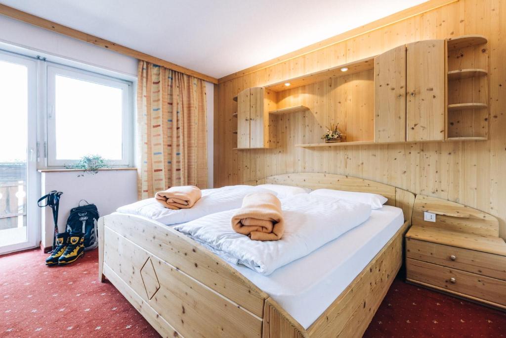 a bed in a room with wooden walls and cabinets at Hotel Schönwies in Trodena