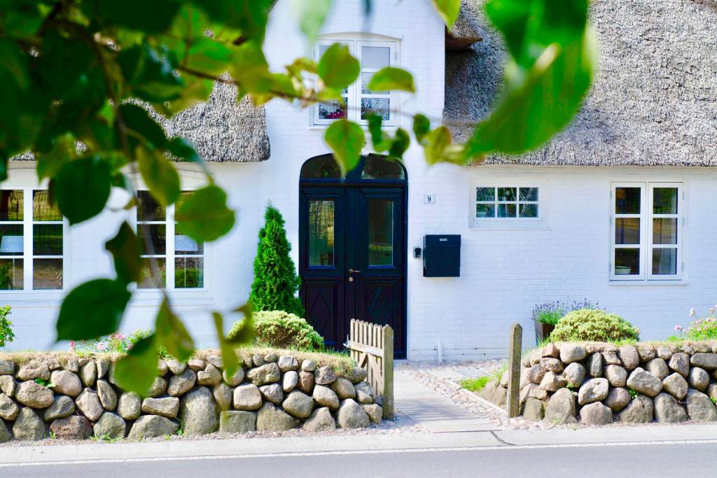 a white house with a blue door and a fence at Ferienwohnungen Bosbuell Huus in Bosbüll