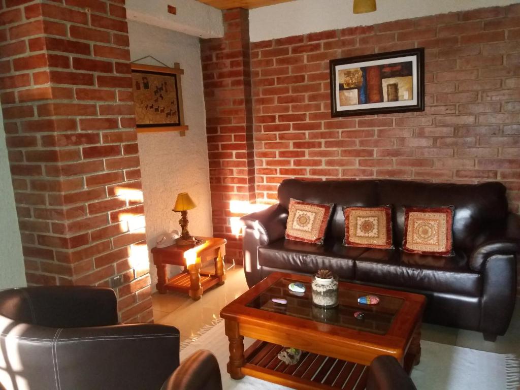 een woonkamer met lederen meubels en een bakstenen muur bij Hostal Balmaceda La Serena in La Serena