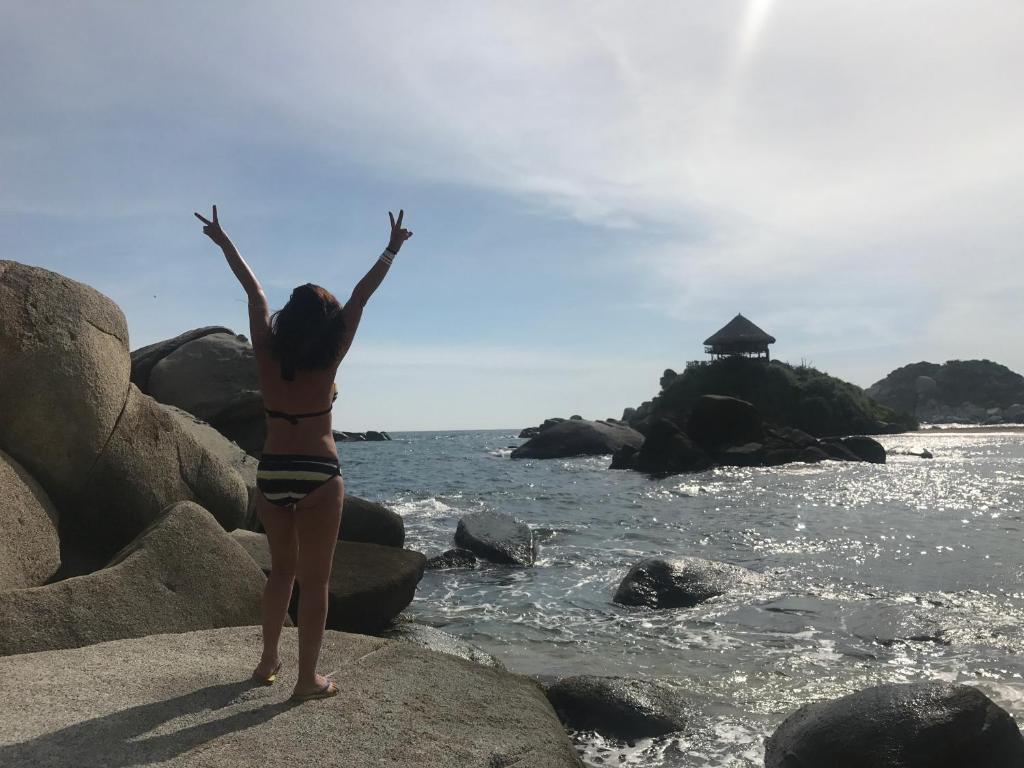 サンタ・マルタにあるEdificio Mar de Levaの海辺の岩に立つビキニ姿の女