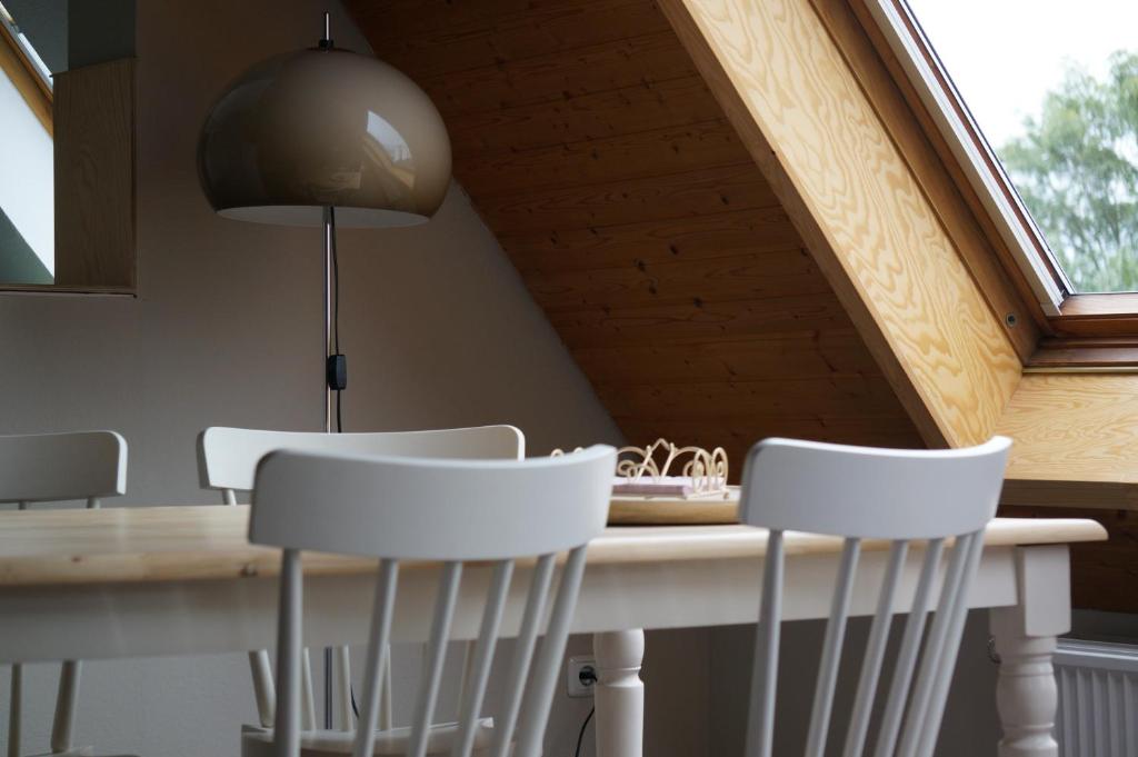 a dining room table with white chairs and a lamp at LilO- mittendrin und ganz dicht bei in Itzehoe