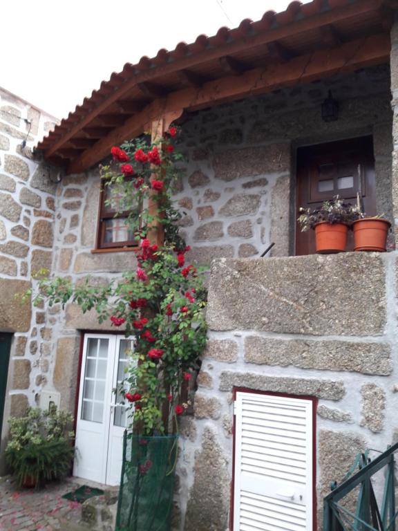 una casa de piedra con flores a un lado. en Casa do Beirado, en Gouveia