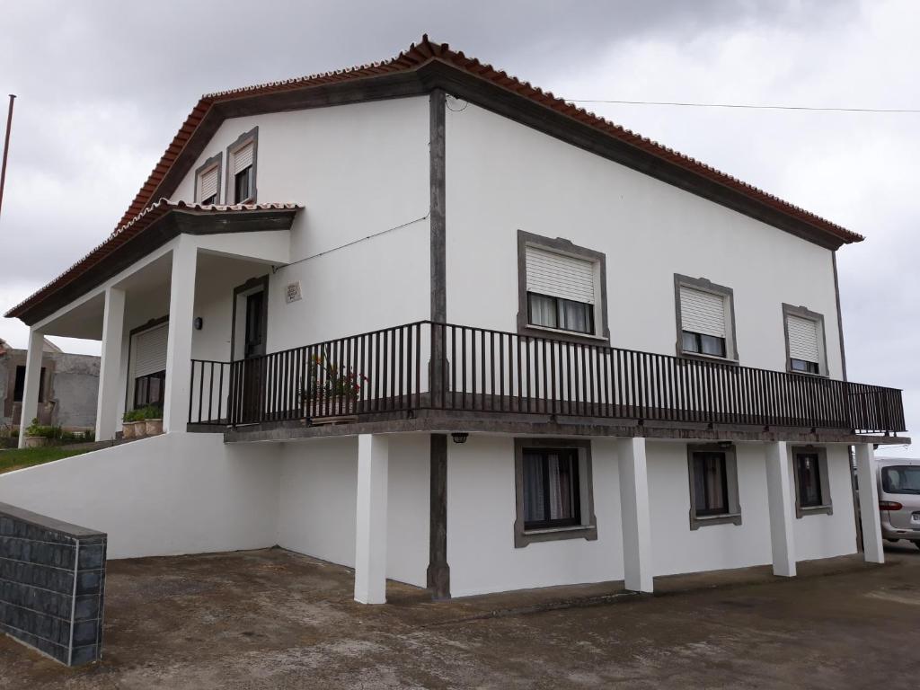 a white house with a balcony on the side at Vivenda Areias in Vila Nova
