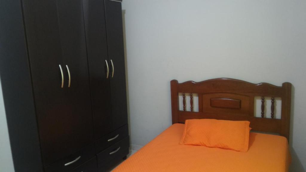クーニャにあるNossa Casaのベッドルーム1室(オレンジ色の枕と黒のキャビネット付きのベッド1台付)