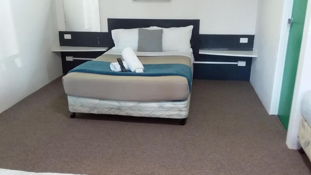 a bed in a room with a white bedspread at Green Door Motel in Albury