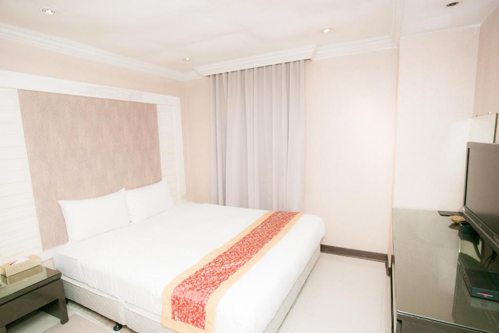 a white bedroom with a bed and a television at 土城飯店 in Tucheng