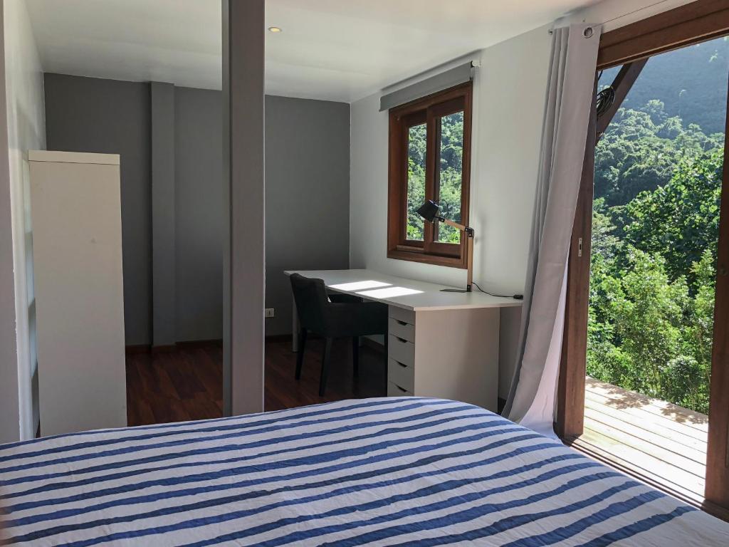 a bedroom with a bed and a desk and a window at La Villa Te Fetia Nui Moorea in Teavaro