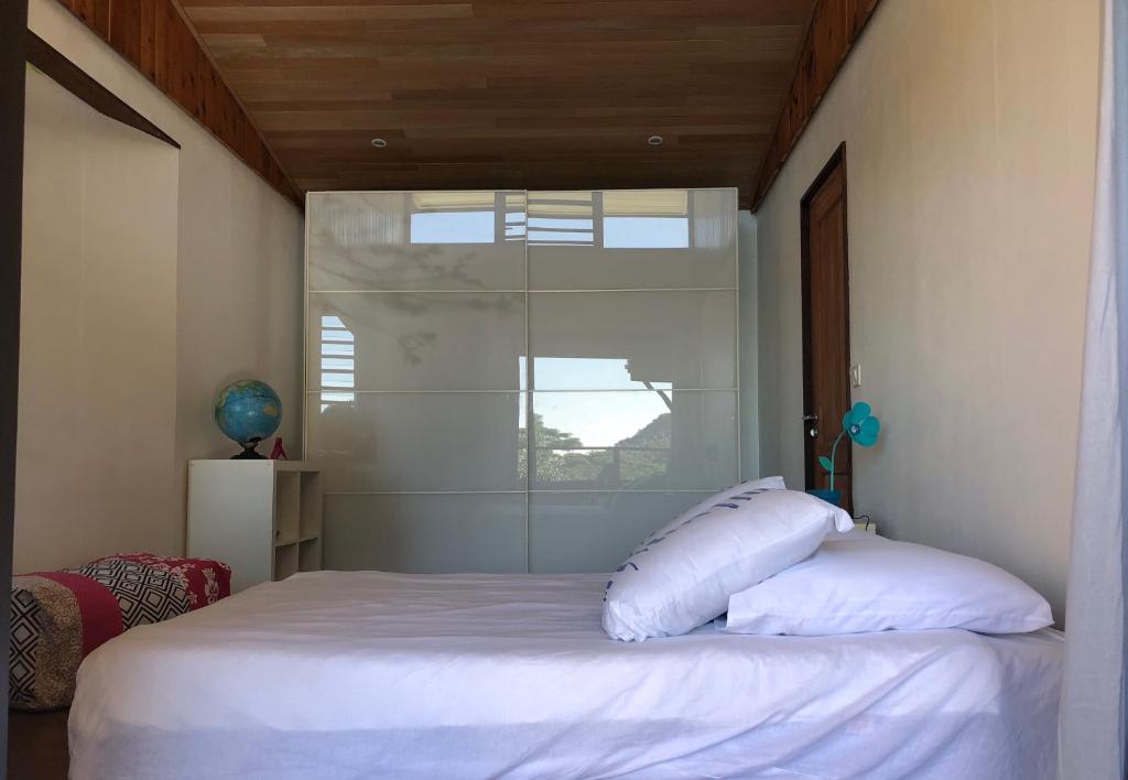 a bedroom with a bed with white sheets and a window at La Villa Te Fetia Nui Moorea in Teavaro