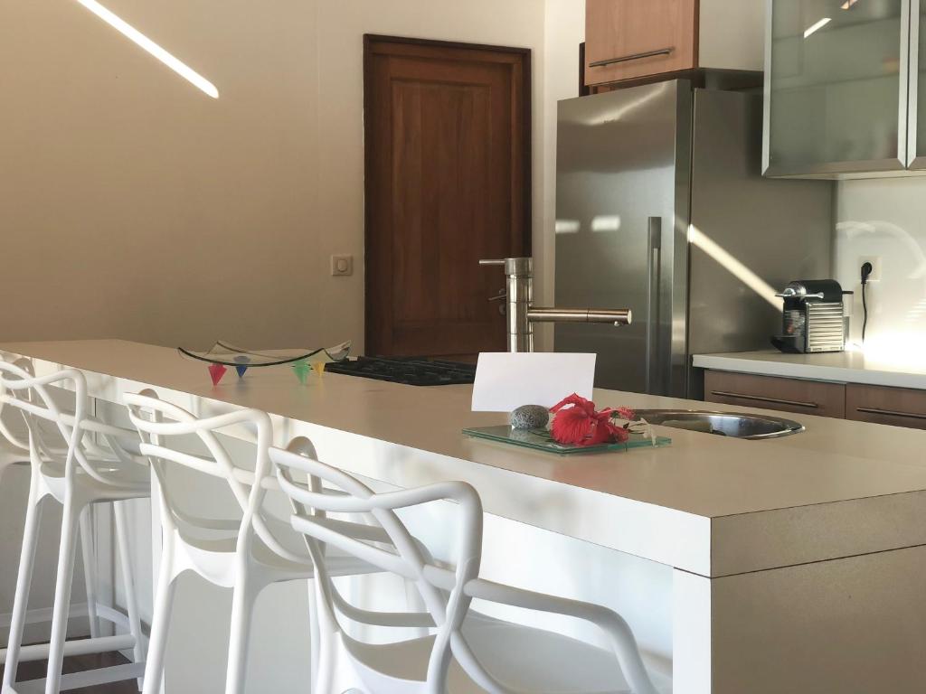 a kitchen with a counter with stools and a refrigerator at La Villa Te Fetia Nui Moorea in Teavaro