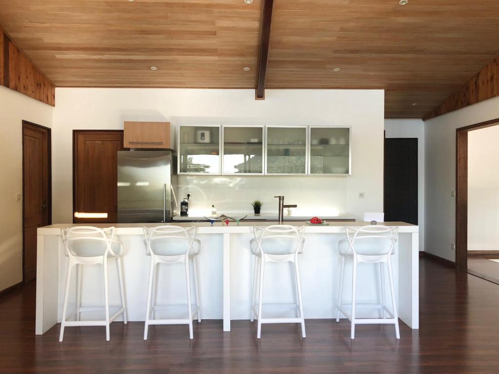 a kitchen with a white island with bar stools at La Villa Te Fetia Nui Moorea in Teavaro