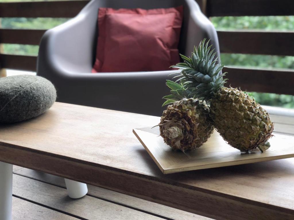 two pineapples sitting on a table next to a chair at La Villa Te Fetia Nui Moorea in Teavaro