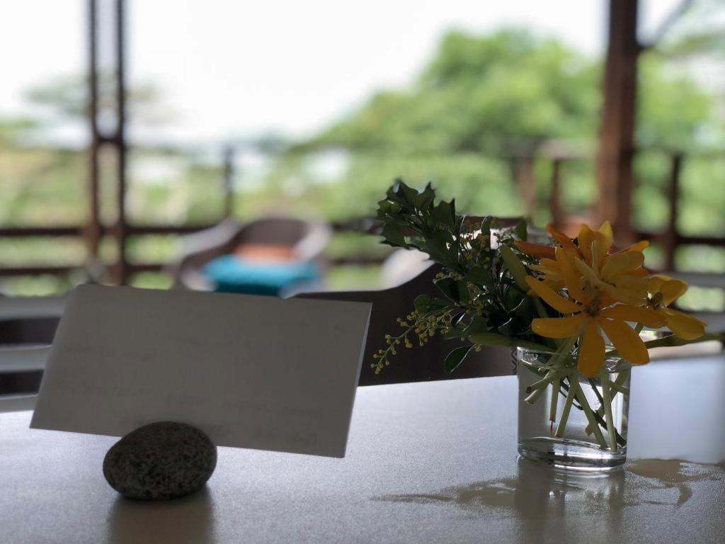 a piece of paper next to a vase of flowers on a table at La Villa Te Fetia Nui Moorea in Teavaro