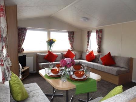 a living room with a table and a couch at Caravan by the sea Trecco Bay in Porthcawl