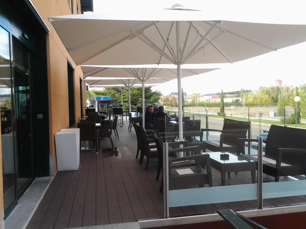 un restaurante con mesas y sillas bajo una sombrilla en Hotel Villa De Ferias, en Medina del Campo