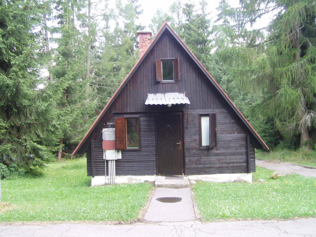 una pequeña casa de madera con una puerta en el césped en Bungalovy pri Hoteli Spojar, en Žiar