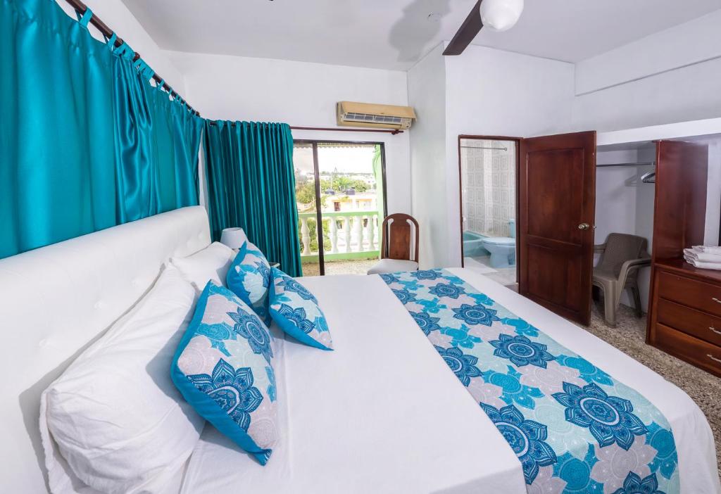 a bedroom with a large bed with blue and white pillows at B&M Setup Hotels in Santo Domingo