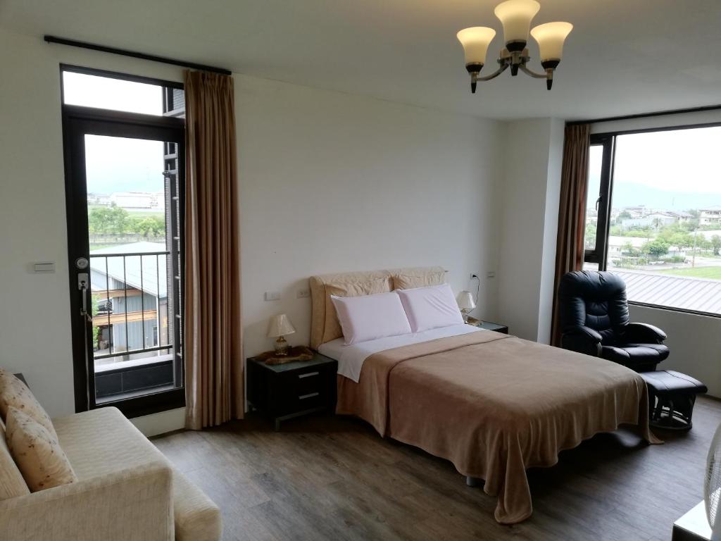 una camera con letto, sedia e finestre di Tata House B&B a Xingjian