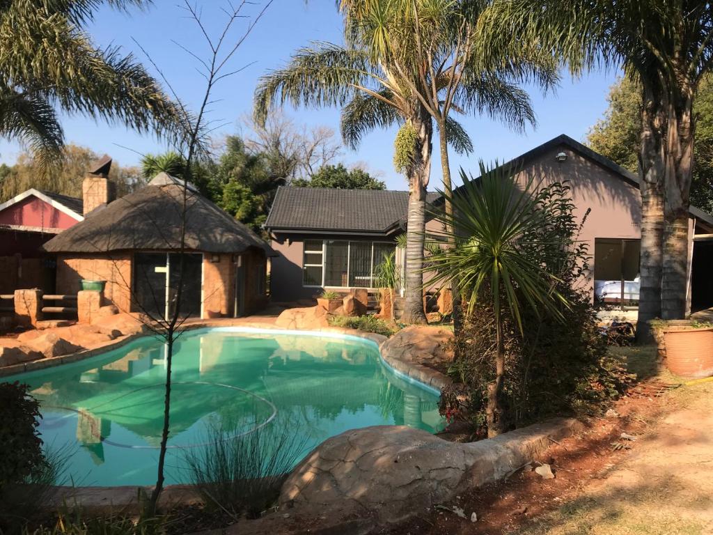 a pool in front of a house with palm trees at Africaren Budget Stay in Kempton Park