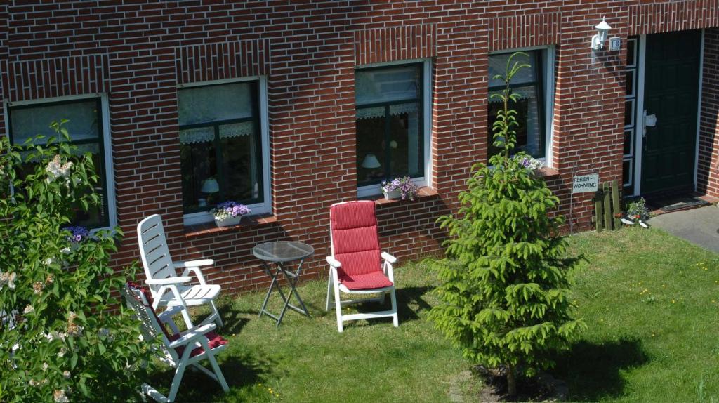 two chairs and a table in front of a brick building at Ferienwohnung Nachbars Garten in Grünendeich