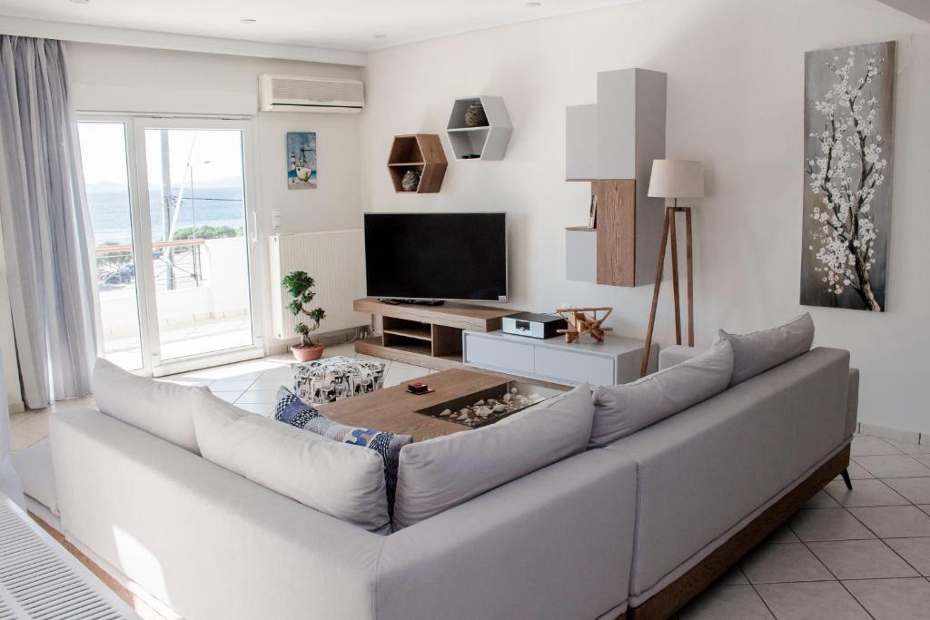 a living room with a white couch and a television at Luxury seaview apartment by the sea in Saronida