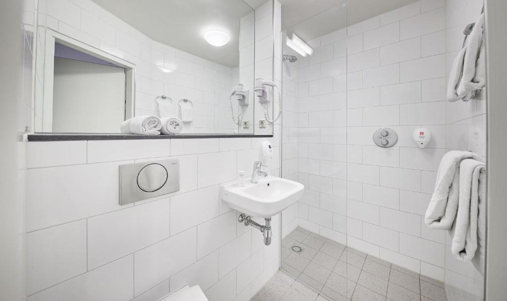 a white bathroom with a sink and a mirror at Singel Hotel Amsterdam in Amsterdam