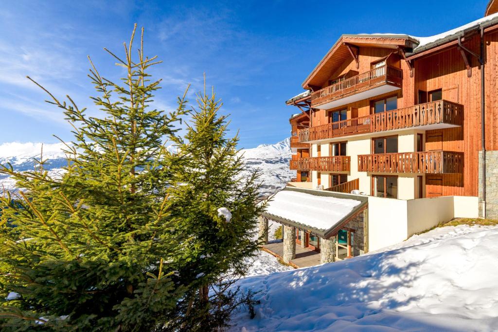 un hotel en la nieve con un árbol de Navidad en travelski home select - Résidence L'Arollaie 4 stars en Peisey-Nancroix