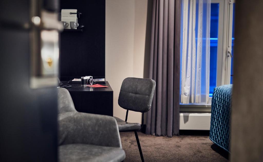 a room with a chair and a desk and a window at Singel Hotel Amsterdam in Amsterdam