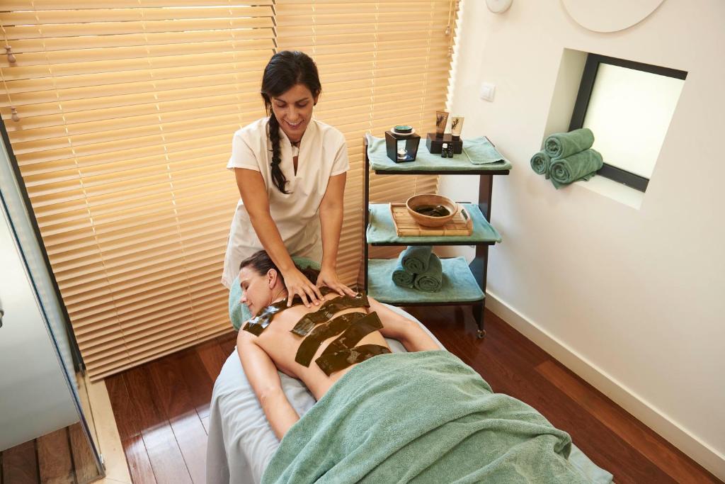 a woman is giving a man a massage at Martinhal Sagres Beach Family Resort Hotel in Sagres