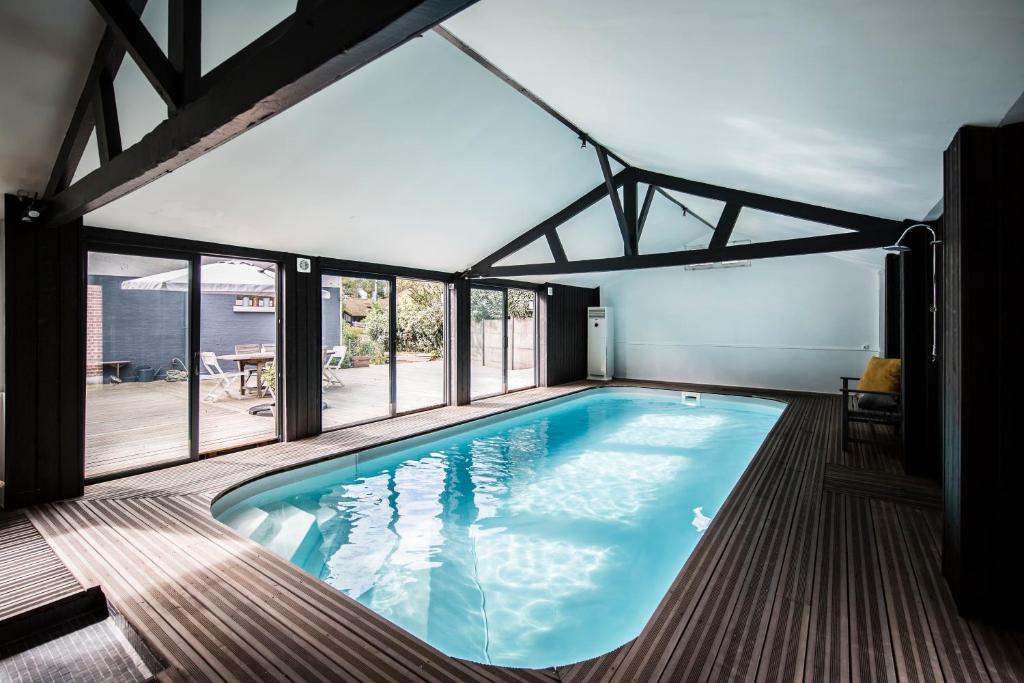 a large swimming pool in a house with windows at La Villa in Mesnil-Val-Plage
