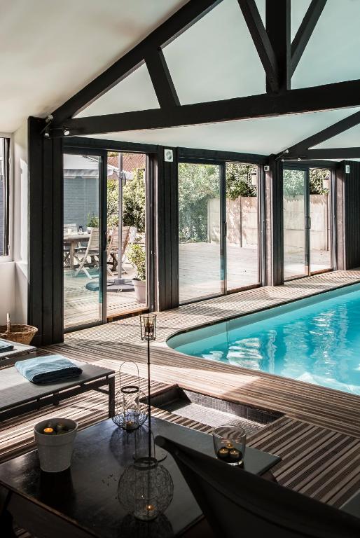 a house with a swimming pool with a table and chairs at La Villa in Mesnil-Val-Plage