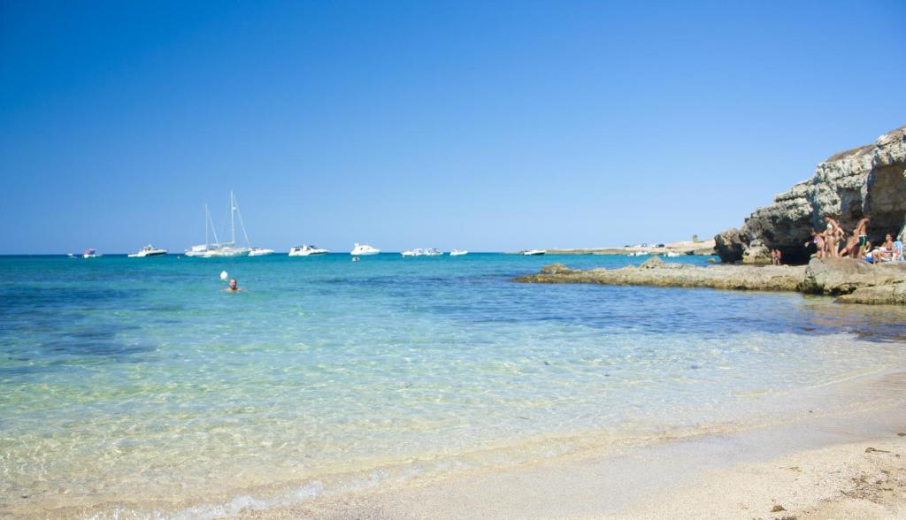 a beach with people swimming in the water at Corvino Resort in Monopoli