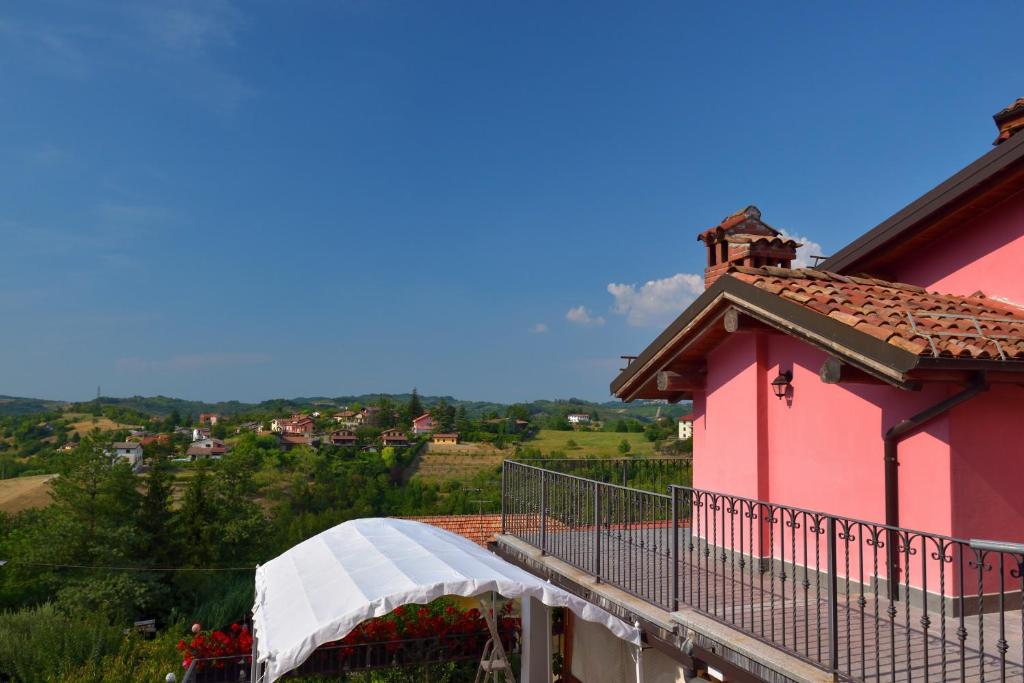 a balcony of a pink house with a white awning at B&B Il Borgo Fiorito in Lerma