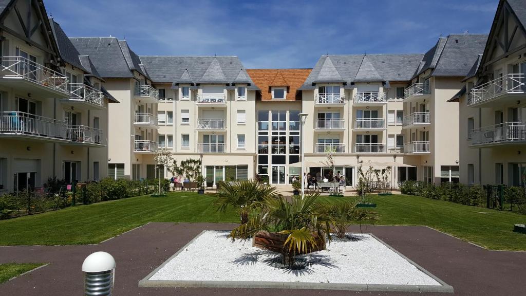 um grande edifício de apartamentos com um parque em frente em Domitys La Plage de Nacre em Courseulles-sur-Mer