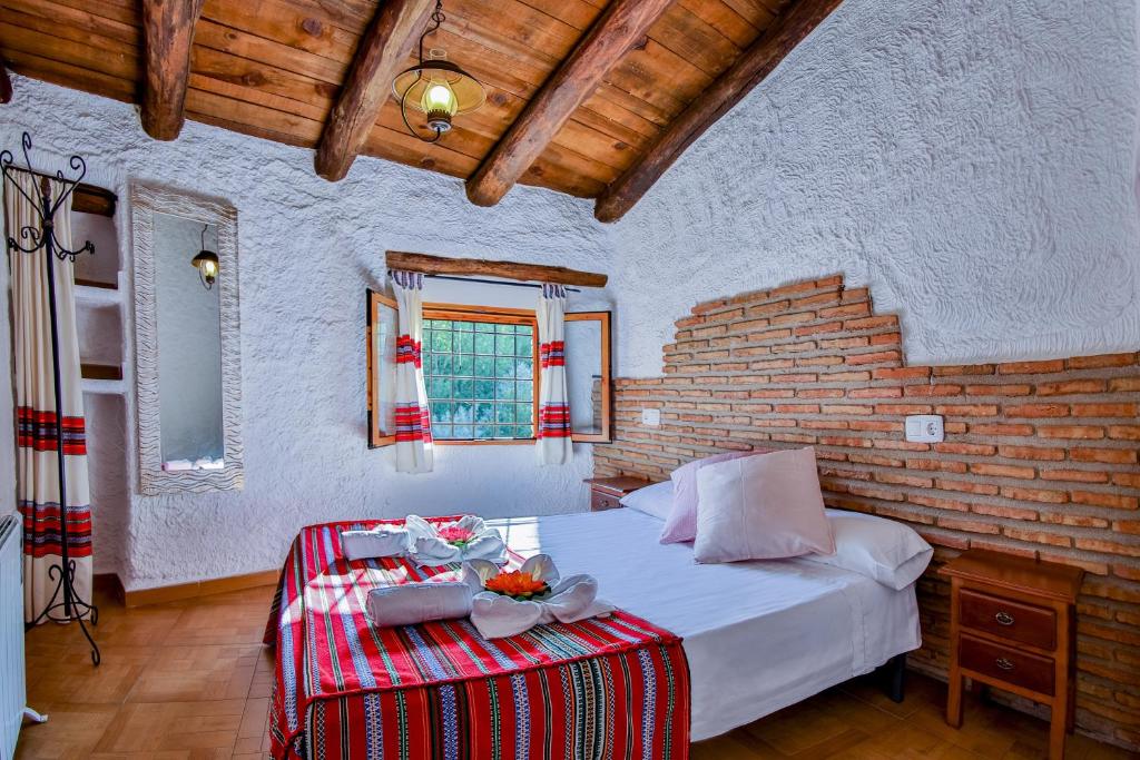 Un dormitorio con una cama y una pared de ladrillo. en Cuevas El Moral, en Castilléjar